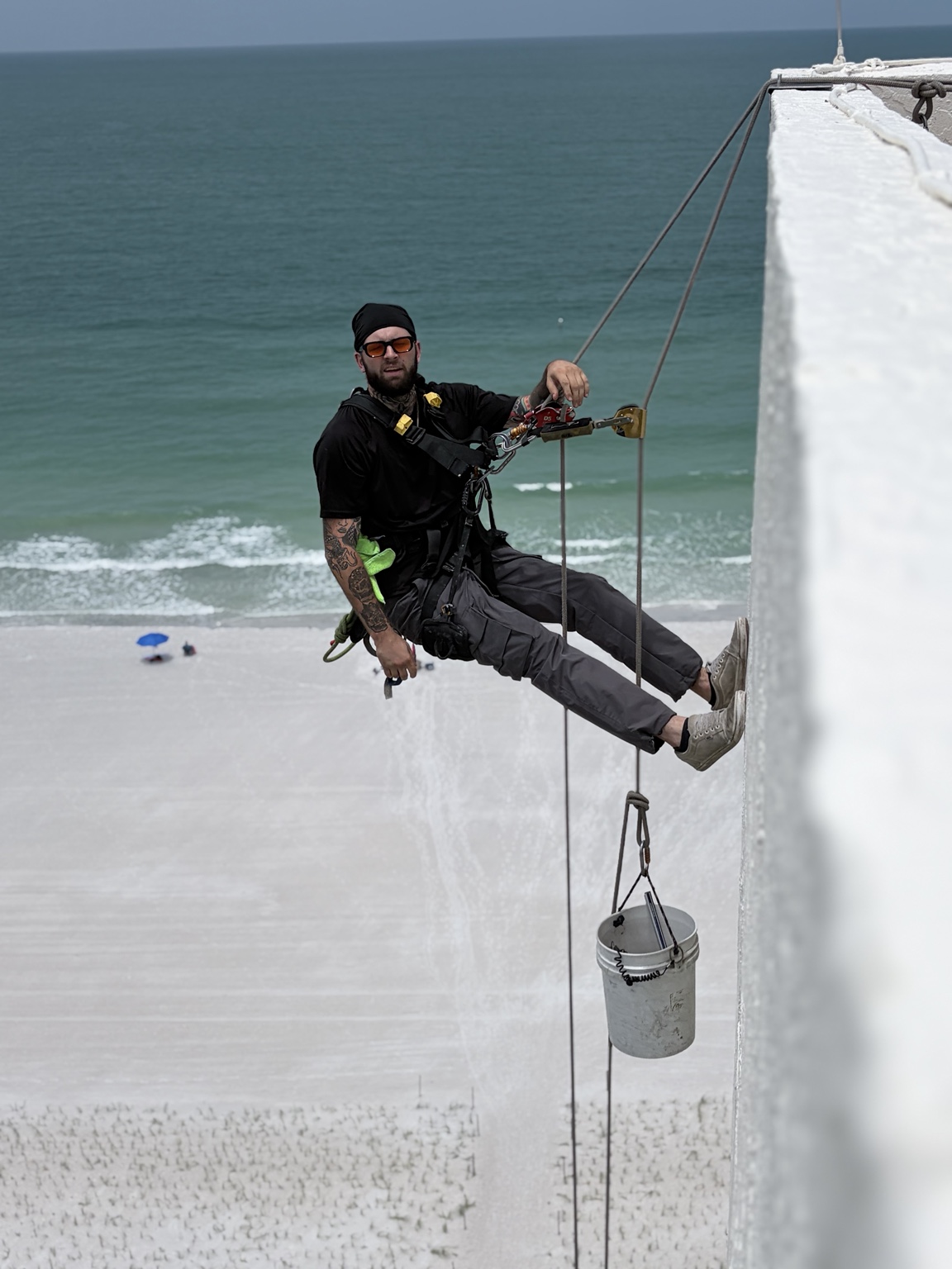 Oceanfront rope-access window cleaner descending a building