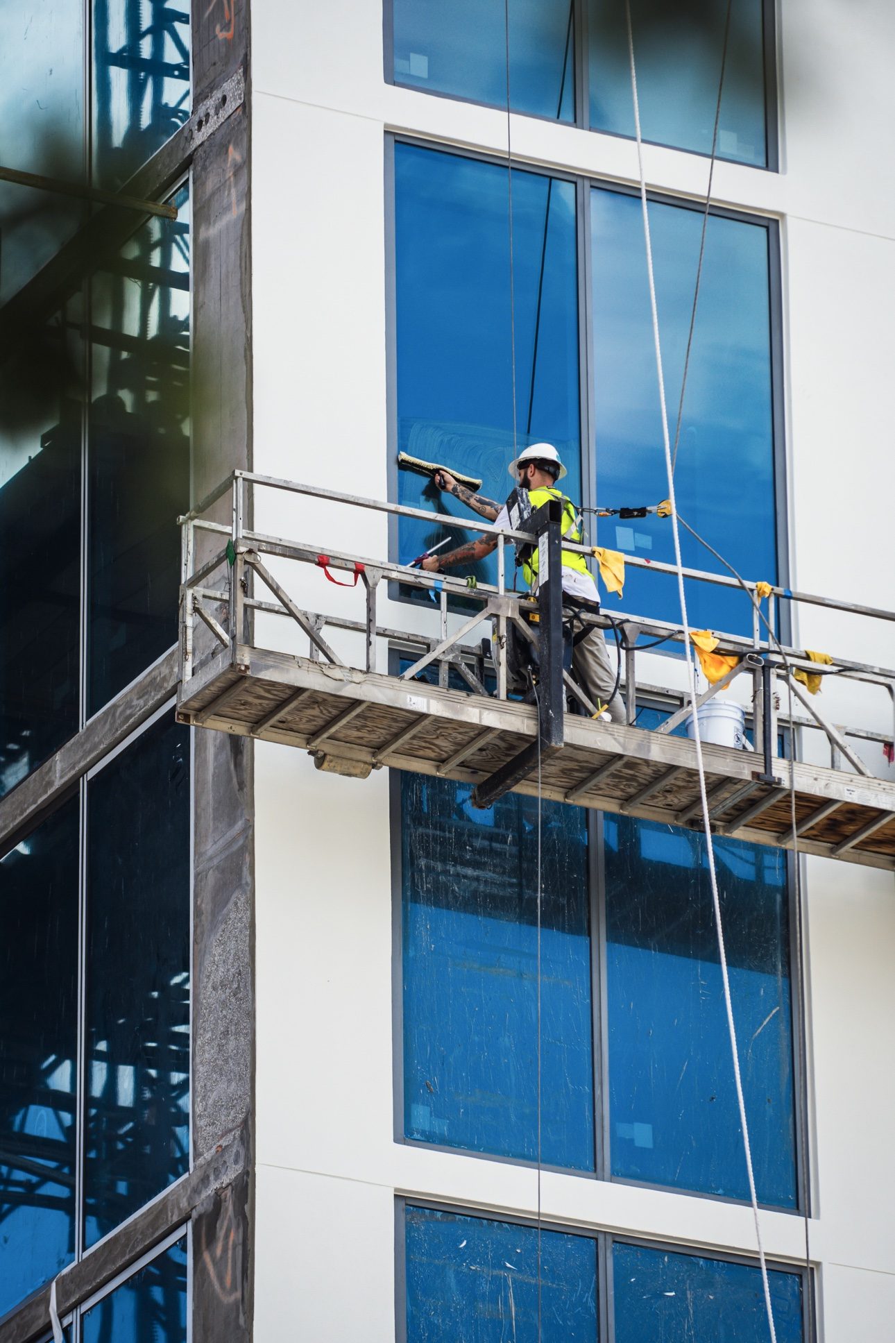 Window cleaner scrubbing high-rise glass from a swing stage
