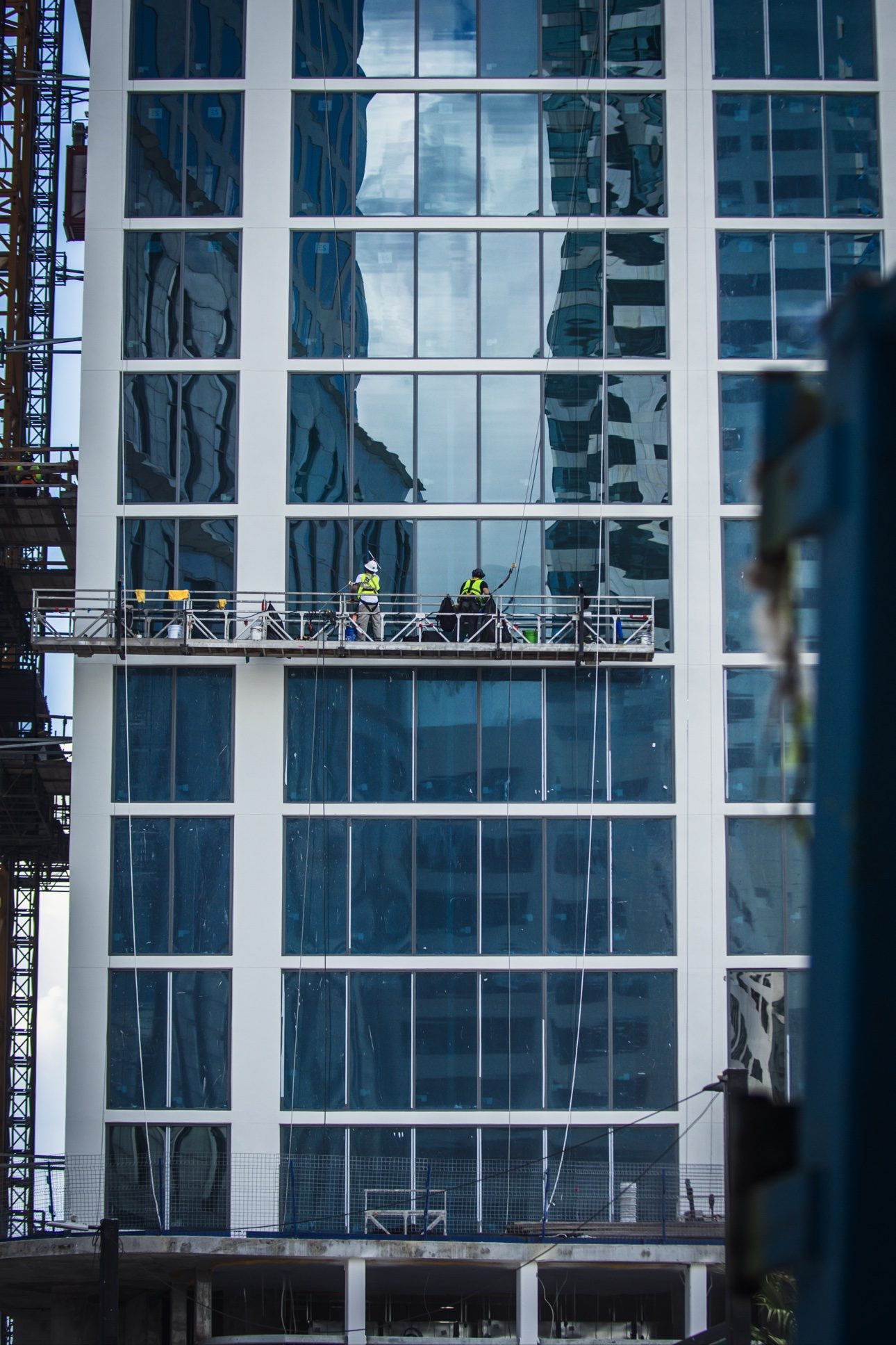Two window cleaners on a swing stage servicing a glass high-rise facade