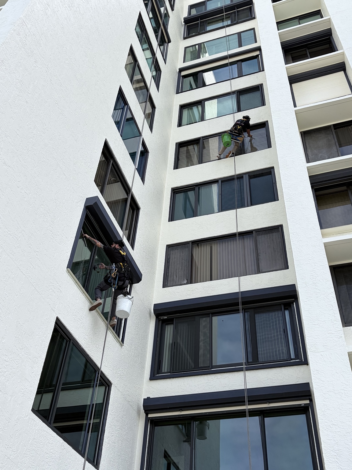 Two rope-access window cleaners servicing a high-rise courtyard